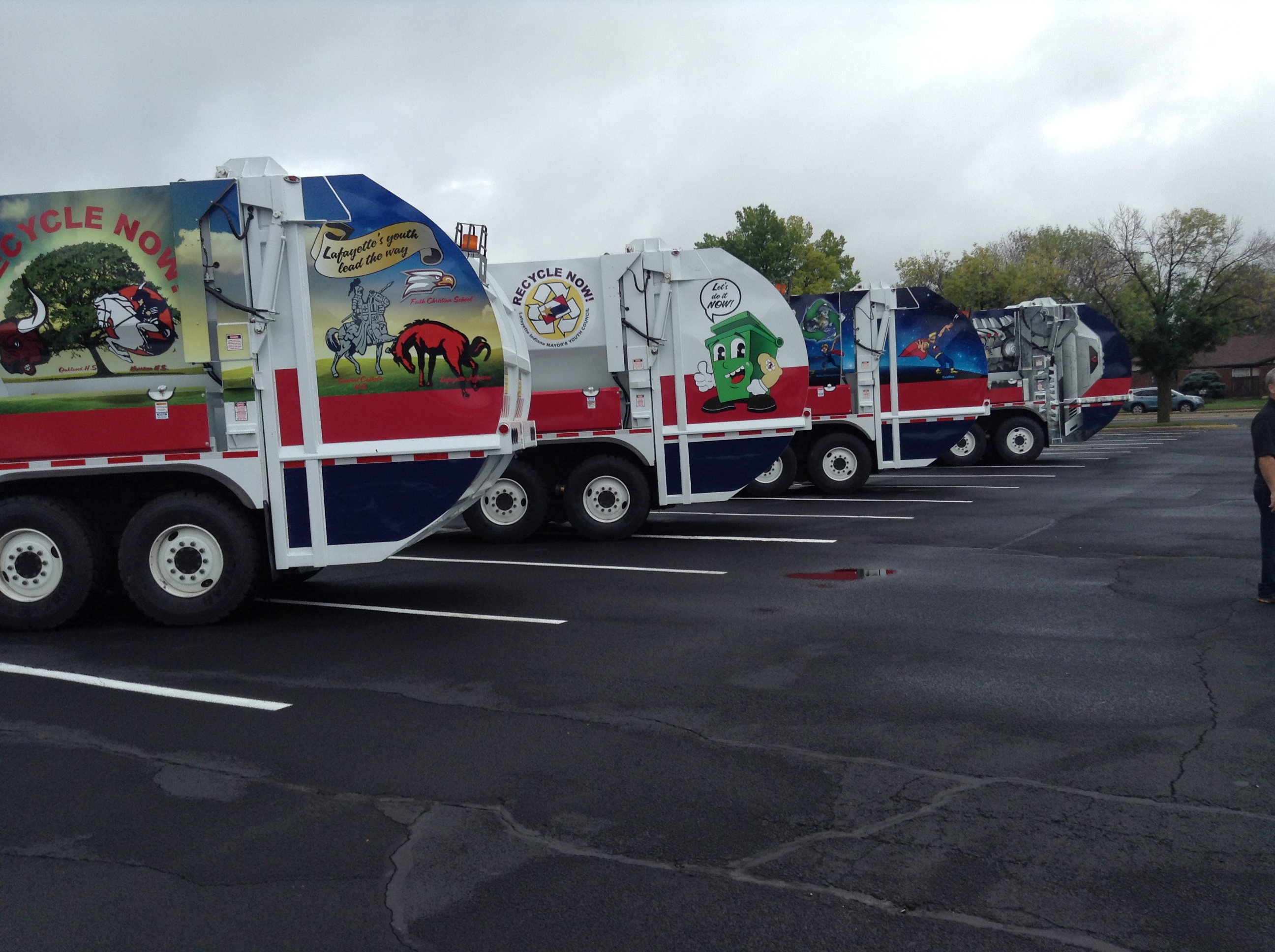 A row of trash trucks parked next to each other
